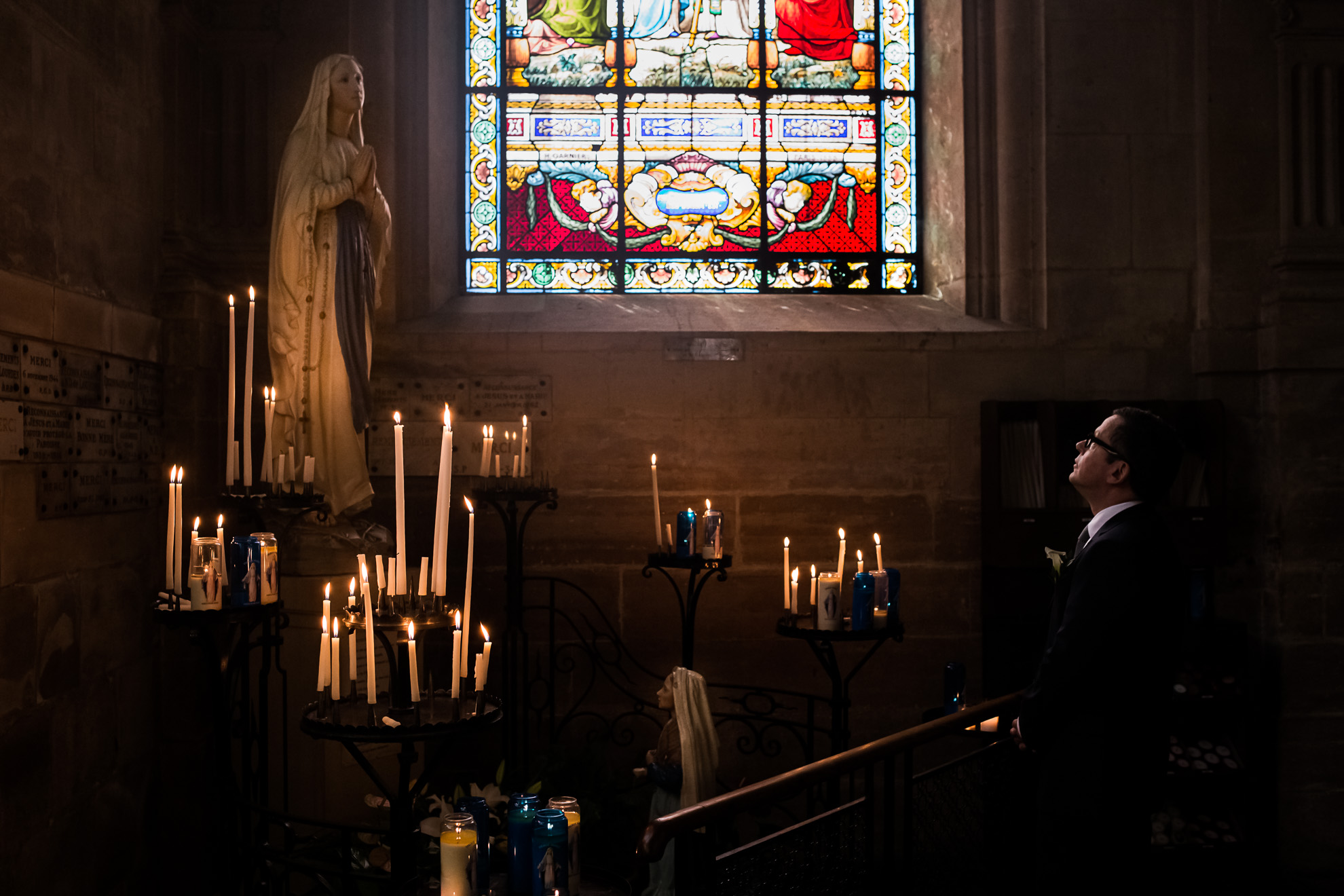 Un homme posant devant un vitrail lors d'un mariage, capturé par un photographe de mariage.