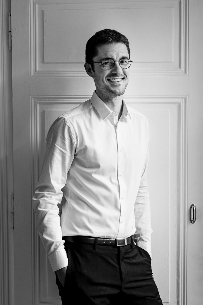 Un homme à lunettes est capturé dans une photographie de mariage en noir et blanc.