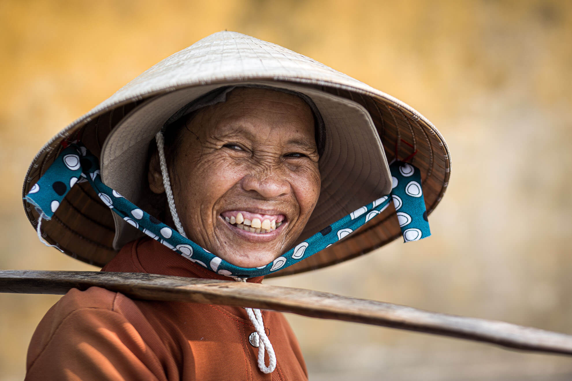 Une femme portant un chapeau conique sourit au Vietnam.