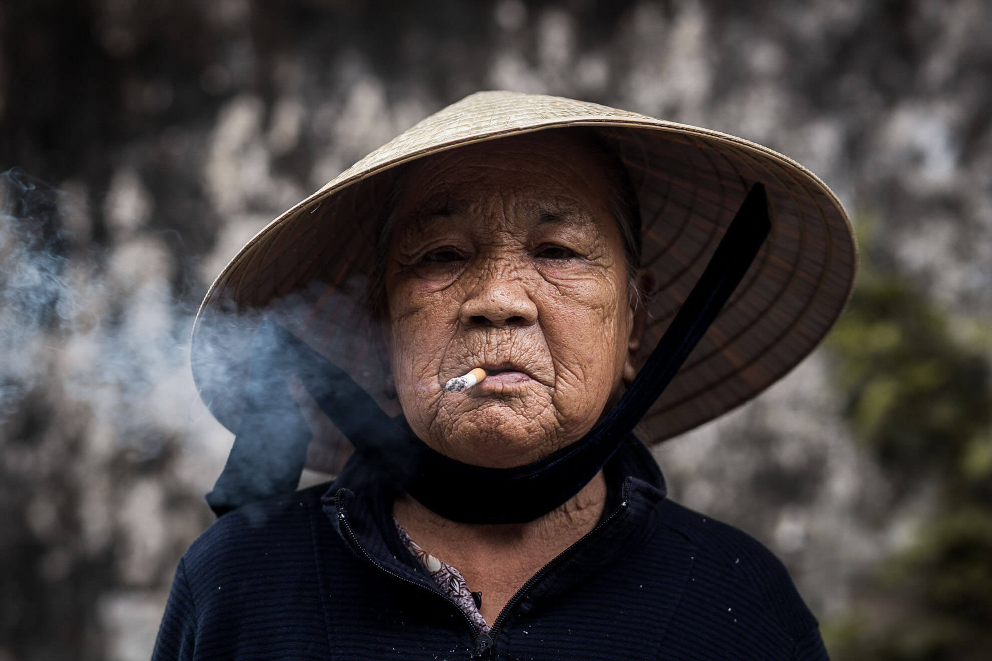 Une vieille femme fume une cigarette.