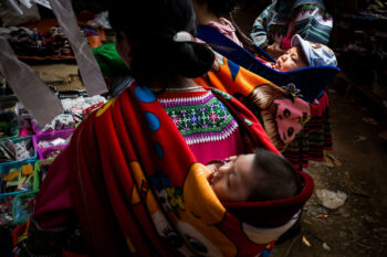 A woman carrying a baby in a baby carrier in Vietnam.