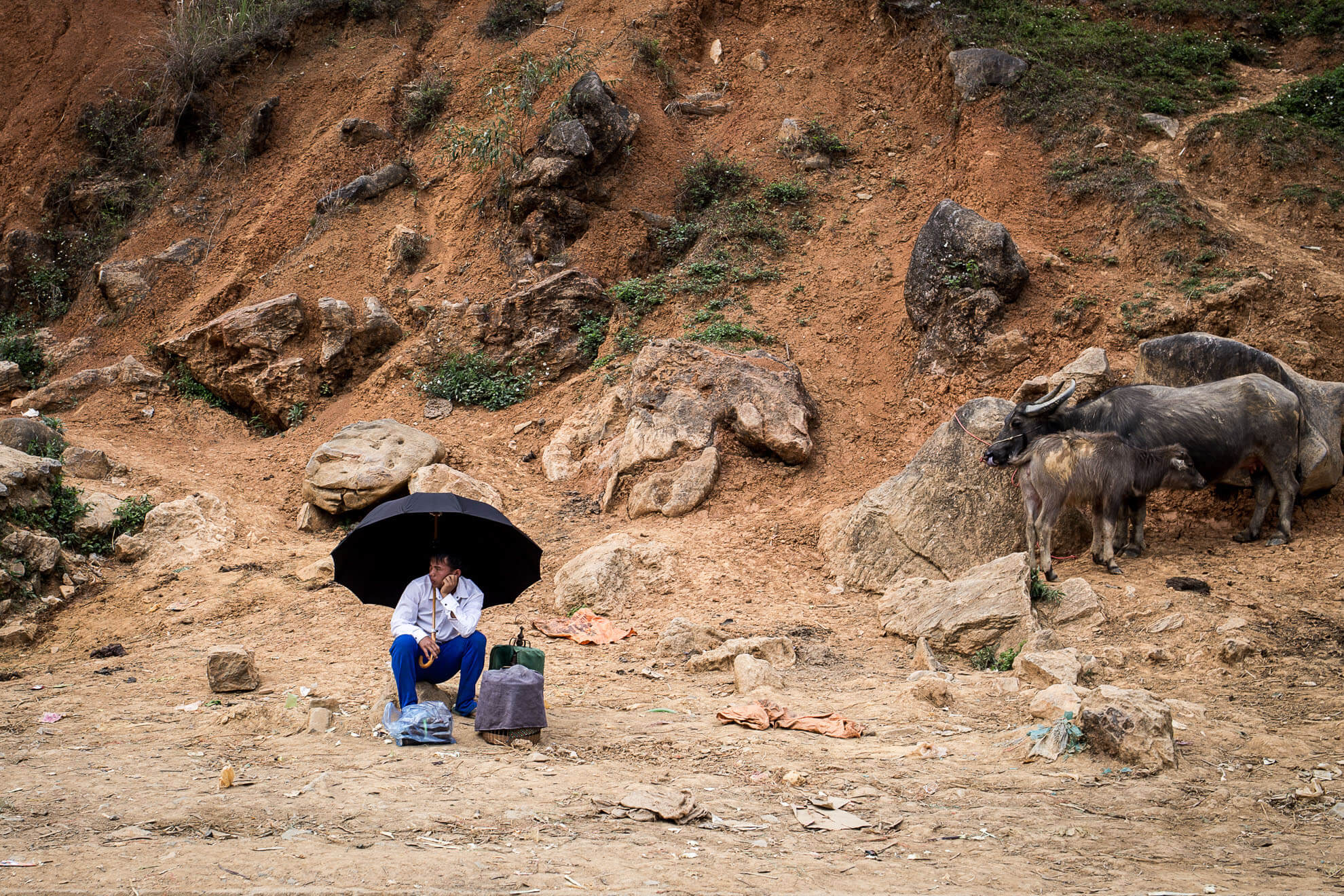 Un homme assis par terre avec un parapluie au Vietnam.