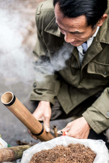 Um homem fuma um cachimbo de bambu no Vietnã.