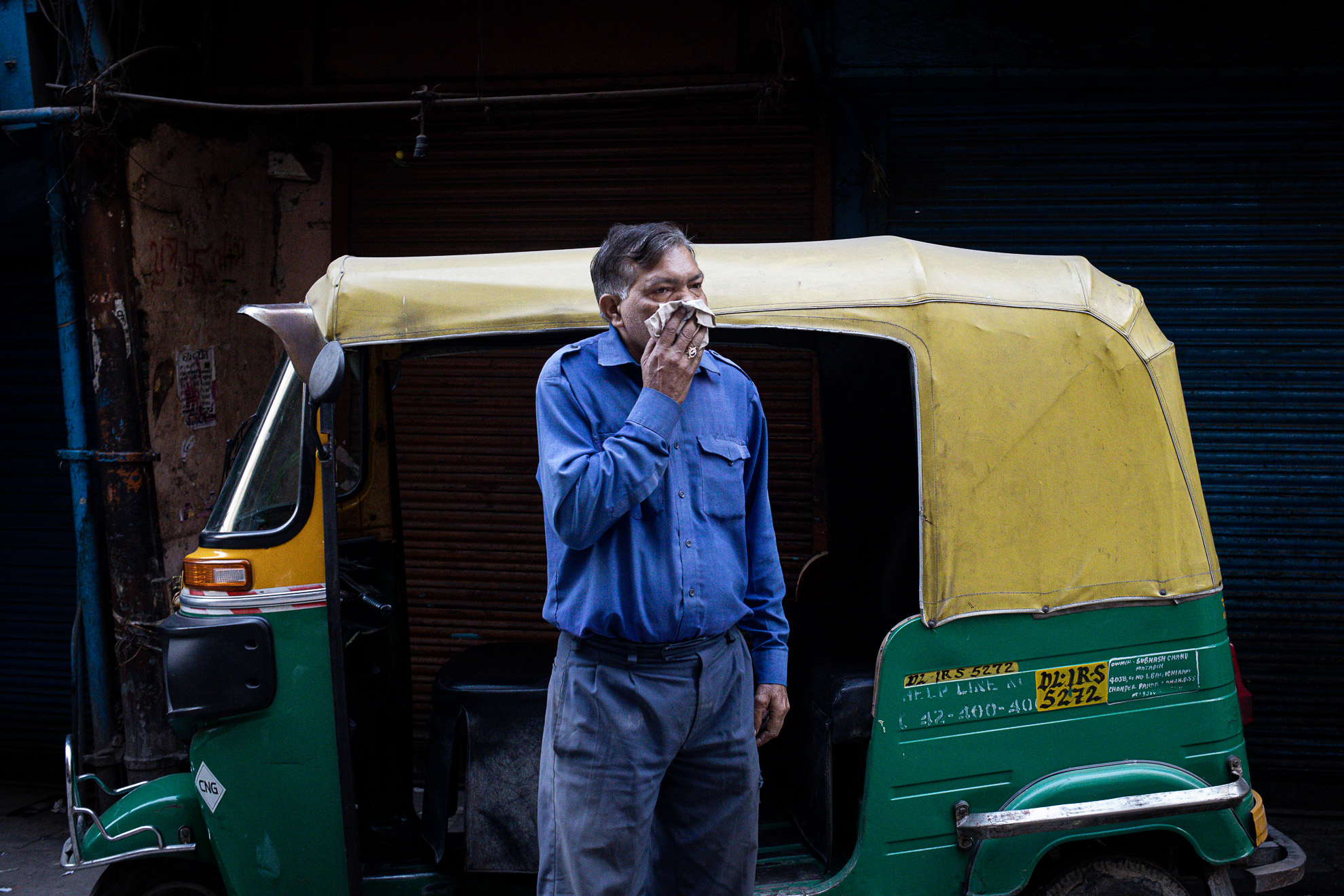 Un homme fumant une cigarette devant un pousse-pousse en Inde.