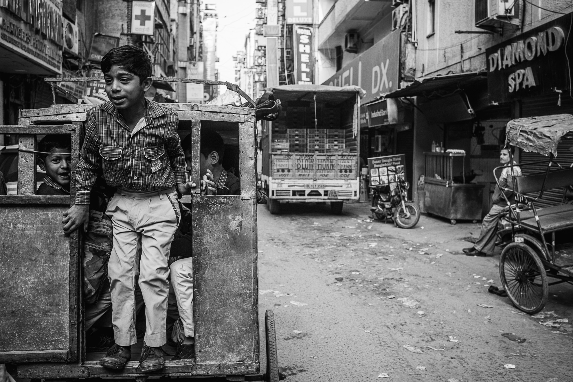 Photographie en noir et blanc d’un garçon chevauchant un pousse-pousse en Inde.