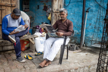 Deux hommes indépendants assis sur une chaise lisant un journal.