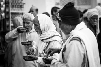 Photographie en noir et blanc d’hommes mangeant de la nourriture sur un marché indien.