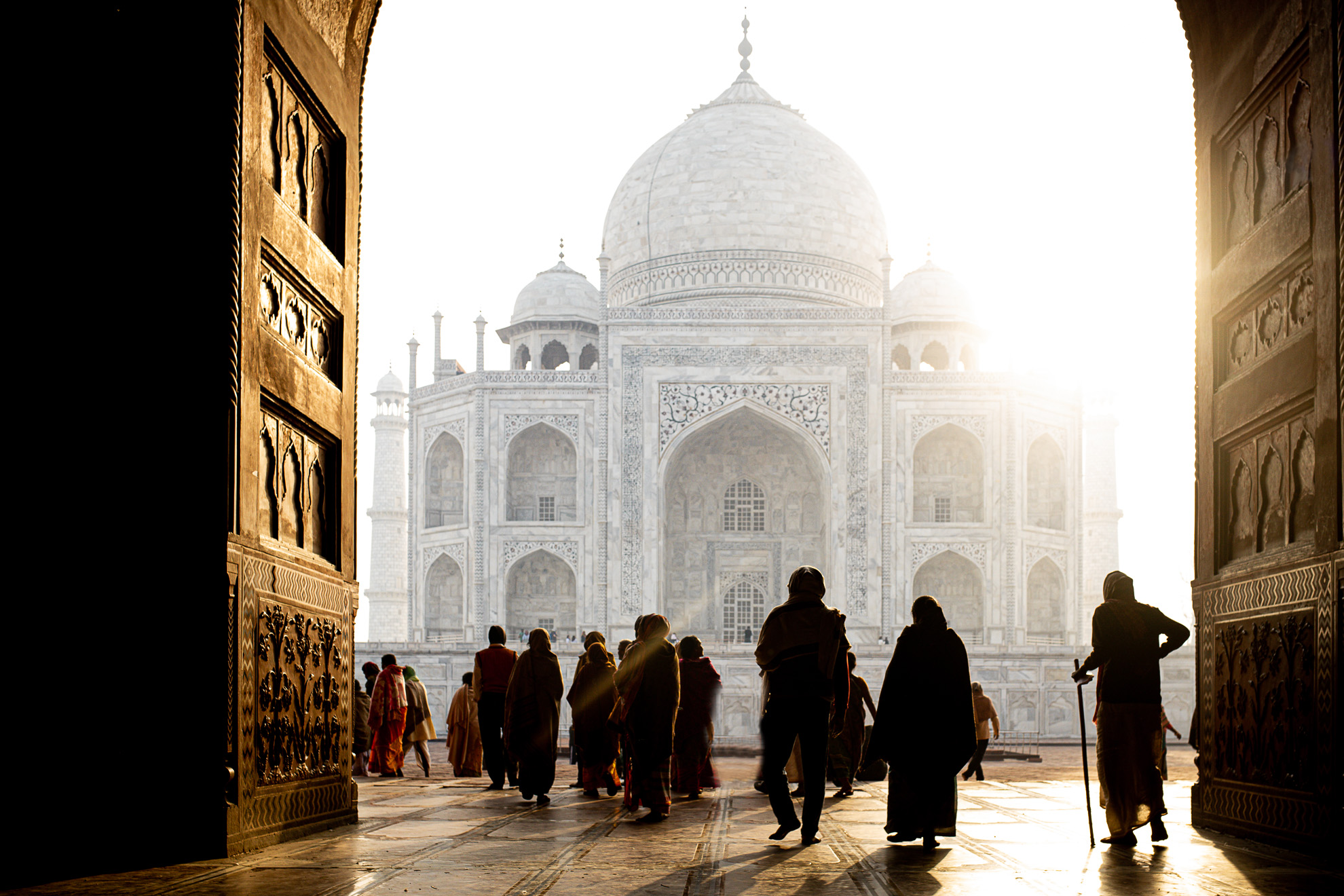 Un groupe de personnes marchant sous une arcade menant au Taj Mahal en Inde.