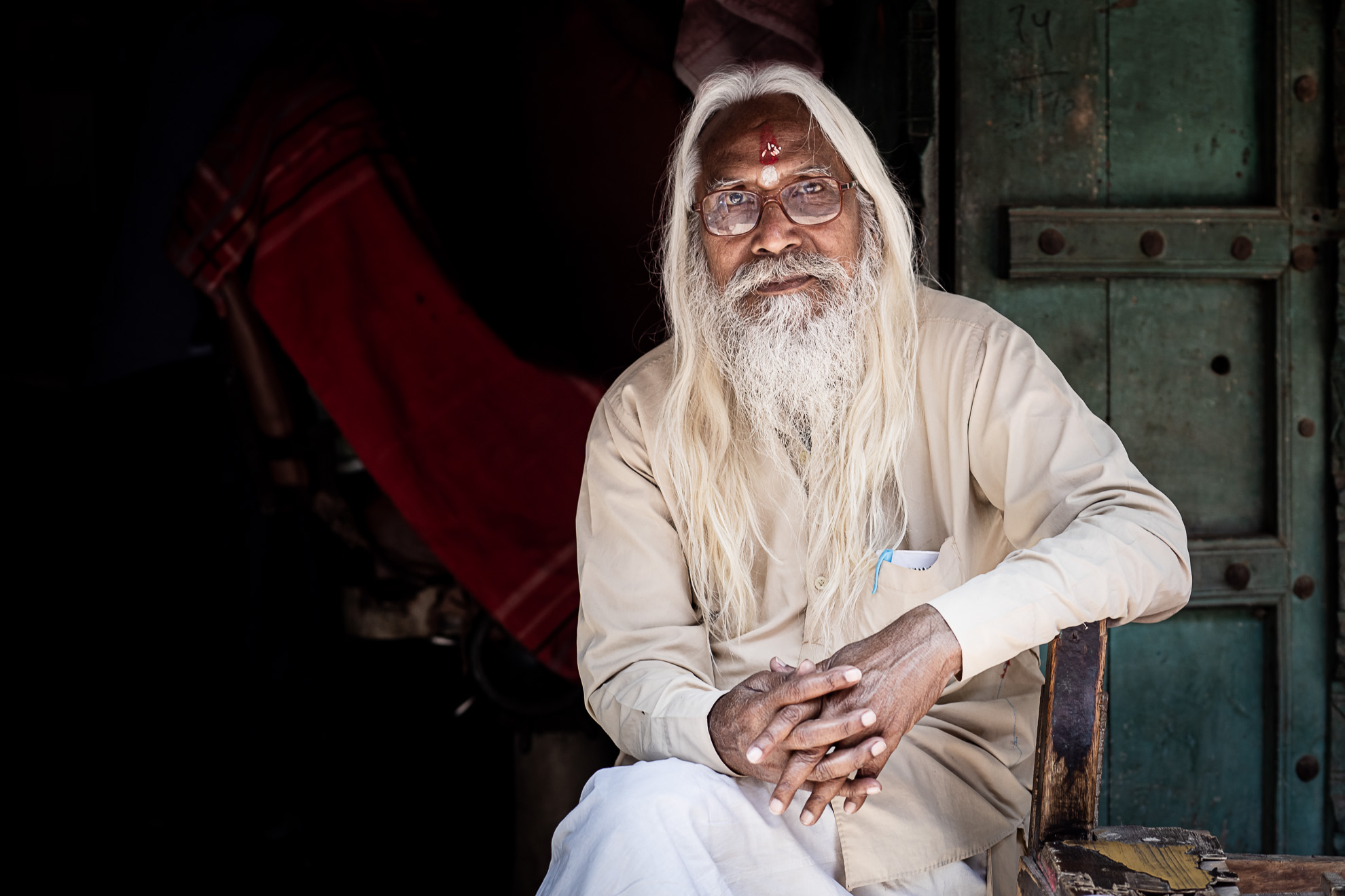 Un Indien assis sur une chaise avec une barbe blanche qui reflète son âge distingué.