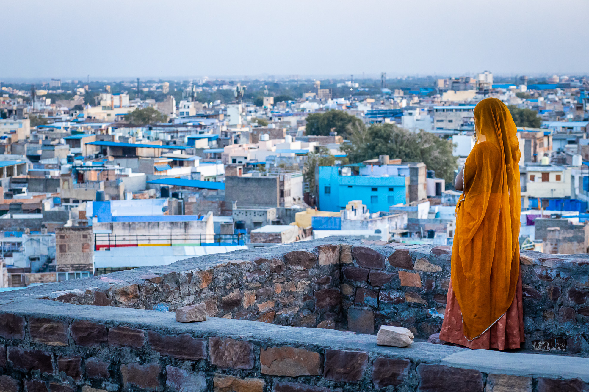 Une femme en sari orange surplombant la ville de Jodhpur, en Inde.