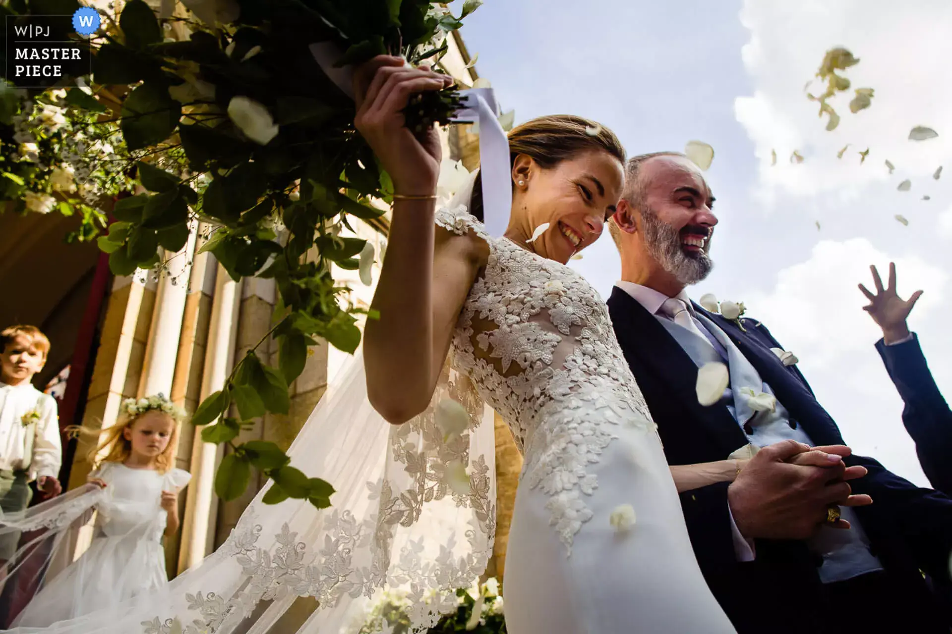 La sortie des mariés de l'église accompagné par les pétales de fleurs.