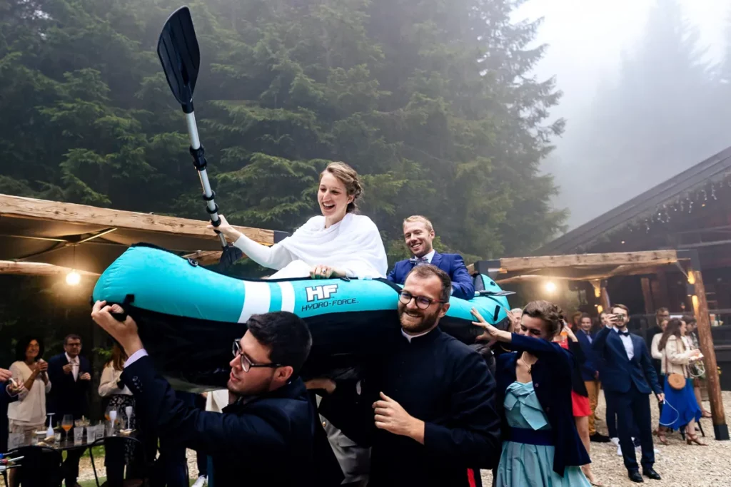 Les invités et le prêtre portent les mariés dans un kayak dans le domaine de montagne.