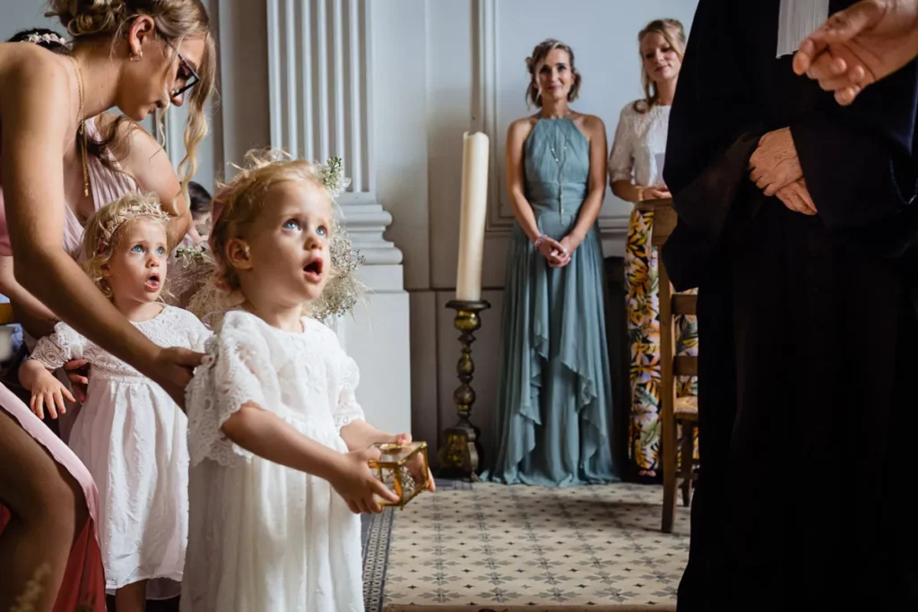 Une petite fille se tient à côté d’un homme vêtu d’une robe blanche.