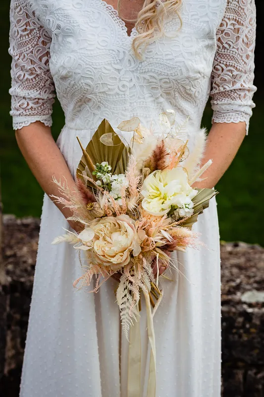 Une mariée en robe blanche tenant un bouquet de fleurs.