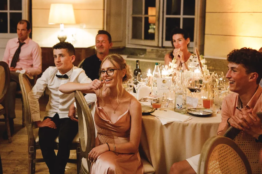 Un groupe de personnes assises autour d’une table lors d’une réception de mariage.