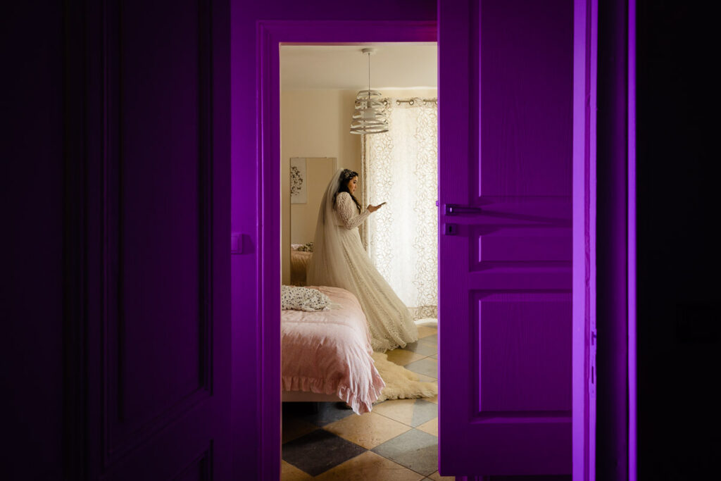 Une femme vêtue d’une robe blanche debout devant une porte violette.