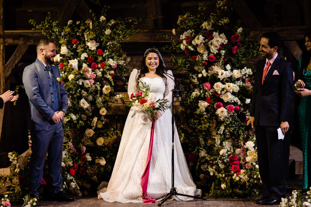 Les mariés se tiennent devant un décor floral lors de leur cérémonie de mariage.