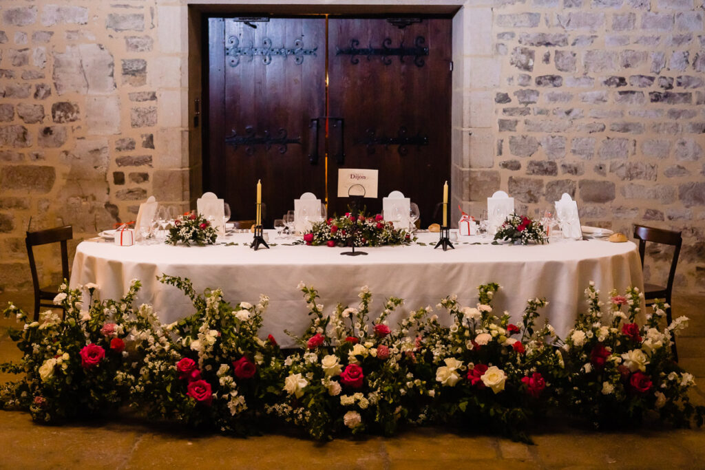 Une table dressée dans une bâtisse en pierre et fleurie.