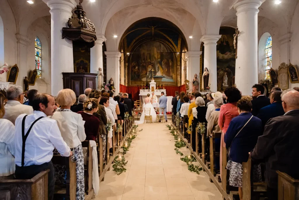 Une cérémonie de mariage dans une église avec des gens assis sur les bancs.