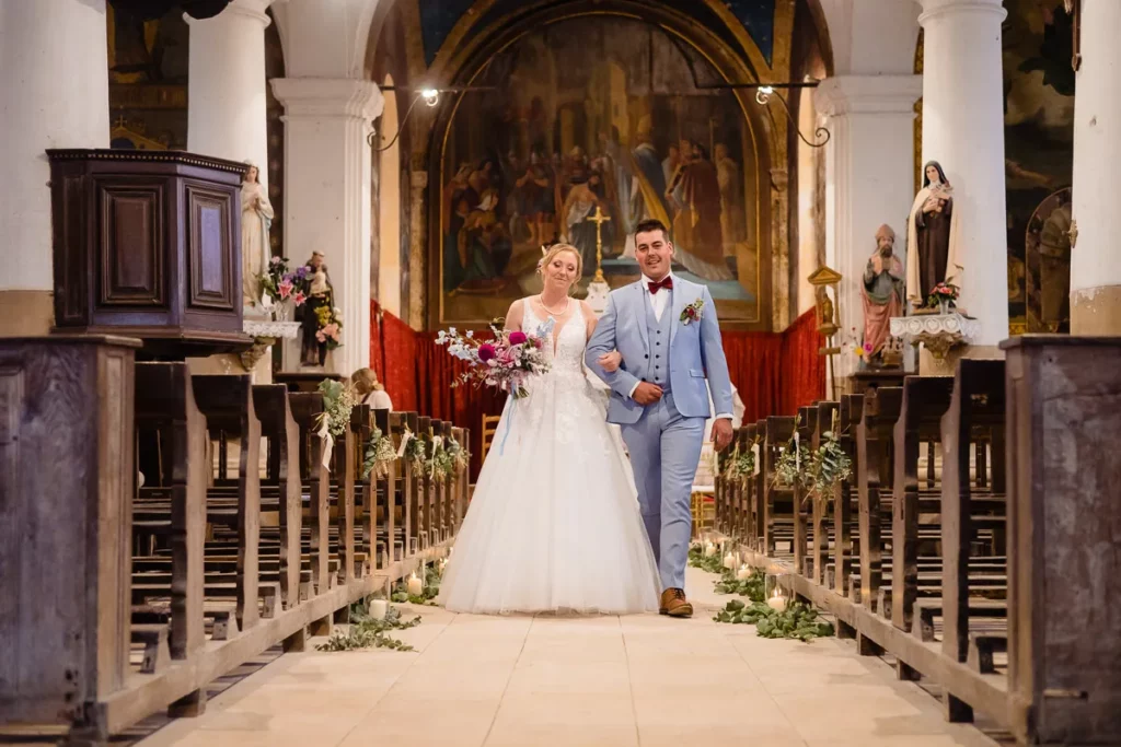 Des mariés marchant dans l’allée d’une église.