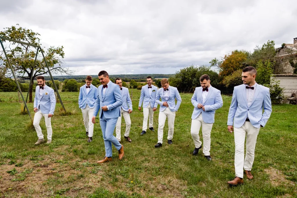 Un groupe d'hommes en costumes bleus et nœuds papillon marchant dans un champ.