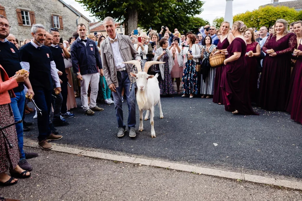 Un homme avec une chèvre devant une foule de gens.