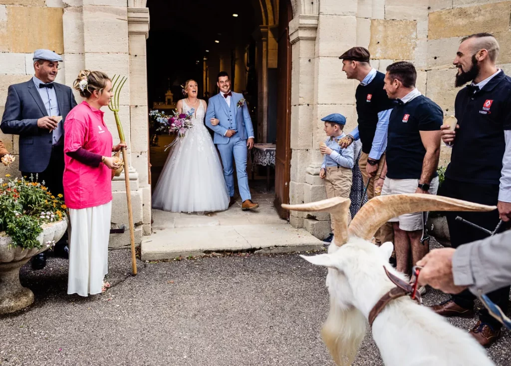 Des mariés avec une chèvre devant eux.