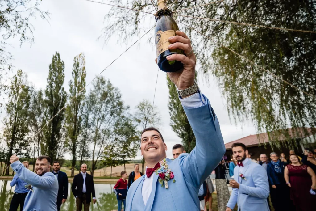 Un marié brandit une bouteille de champagne lors d’un mariage.