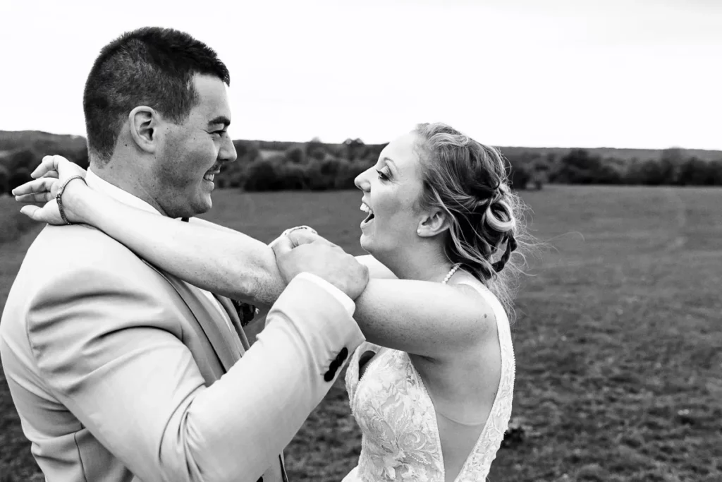 Une mariée et un marié s'embrassant dans un champ.