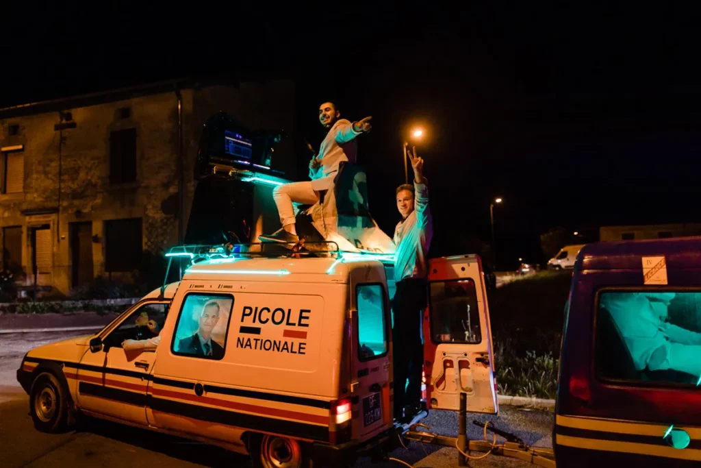 Un groupe de personnes debout au sommet d’une camionnette la nuit.