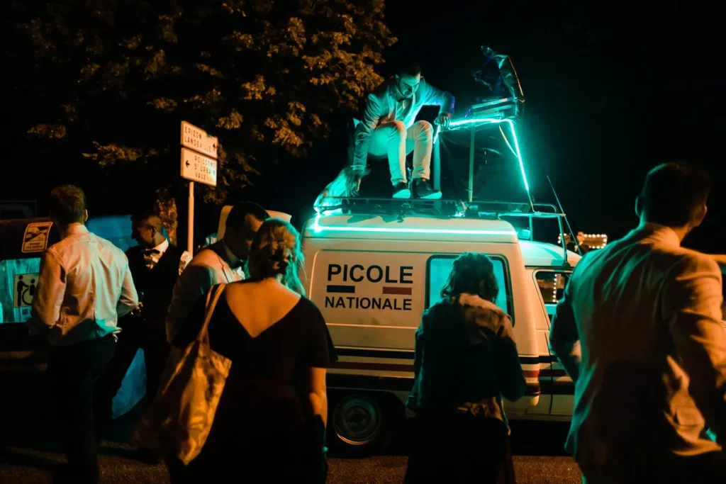 Un groupe de personnes debout autour d’une camionnette la nuit.