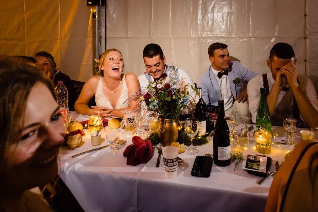 Un groupe de personnes riant autour d’une table sous une tente.