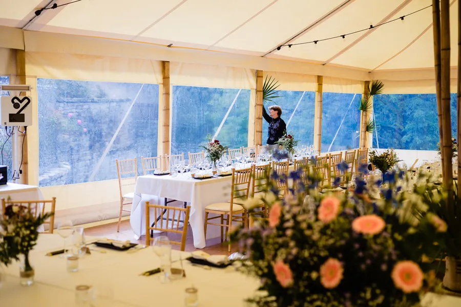 Une réception de mariage sous une tente avec tables et chaises.