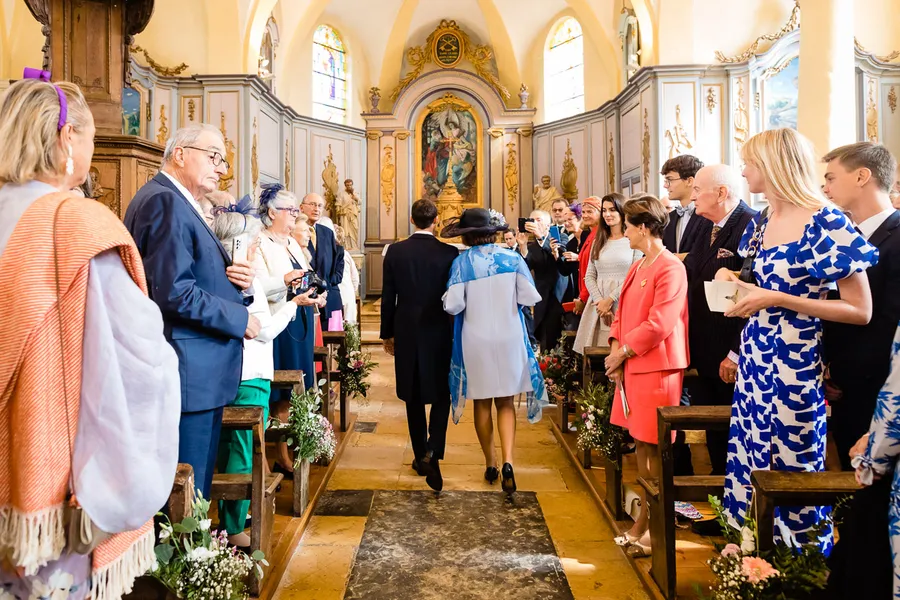 Une cérémonie de mariage dans une église avec des gens marchant dans l'allée.