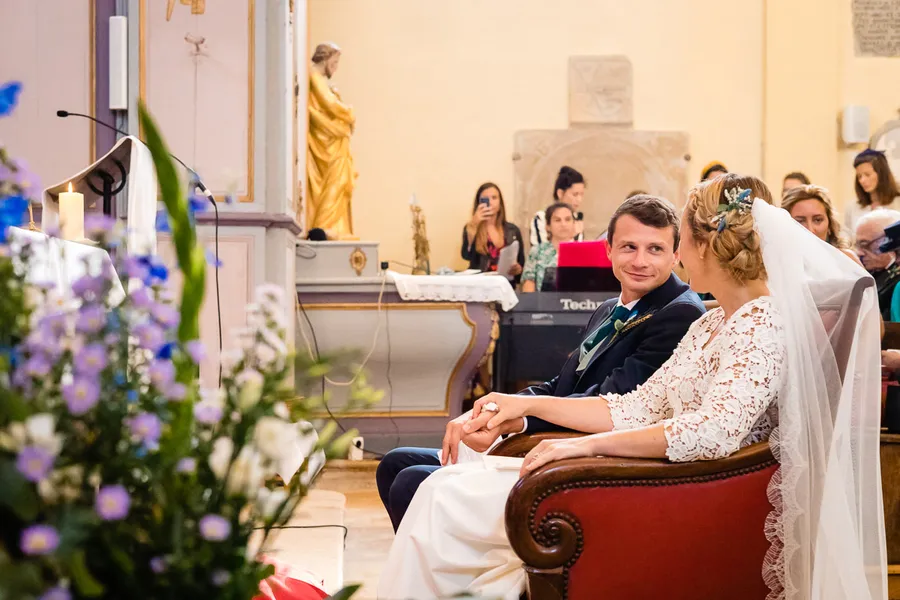 Une mariée et un marié assis sur une chaise dans une église.