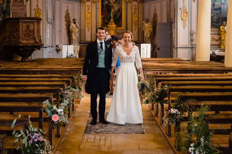 Des mariés marchant dans l’allée d’une église.