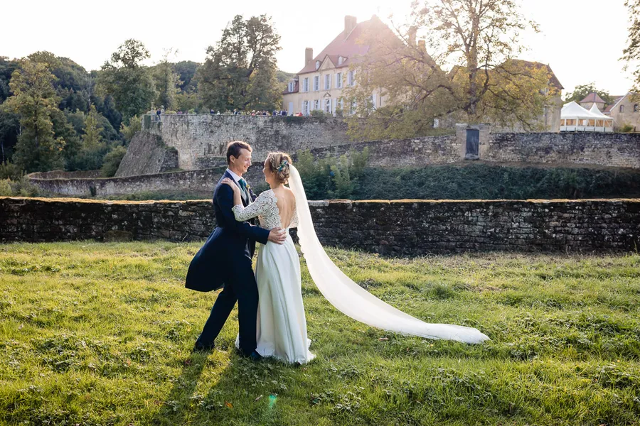 Des mariés debout devant un château.