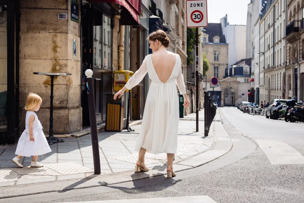 Une femme en robe blanche et une petite fille marchant dans la rue.