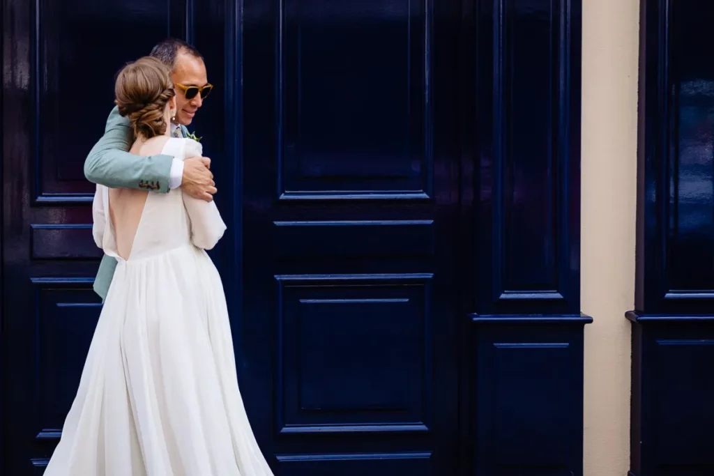 Une mariée et un marié s'embrassant devant une porte bleue.