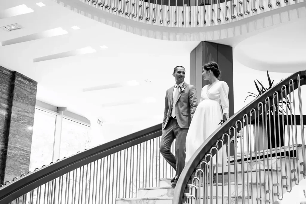 Une mariée et un marié debout dans les escaliers d’un hôtel.