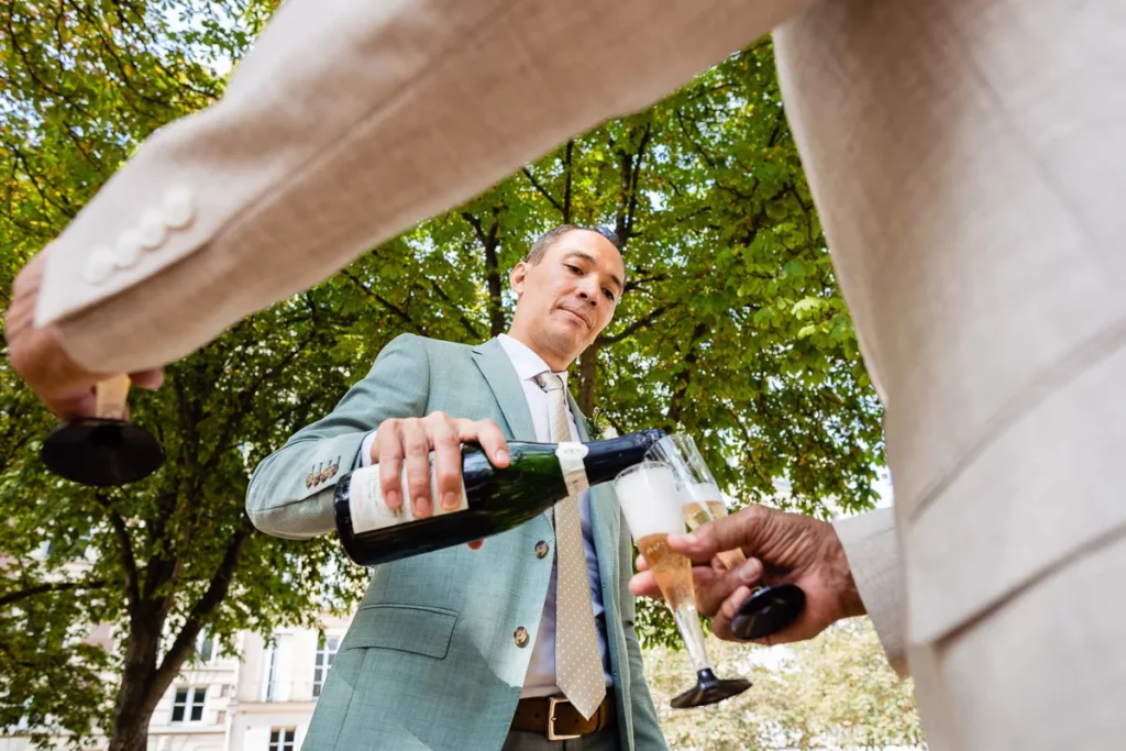 Un homme verse une coupe de champagne dans le verre d'un autre homme.