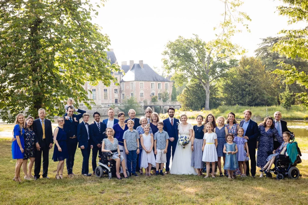 Une photos de groupe devant un château lors d'un mariage.