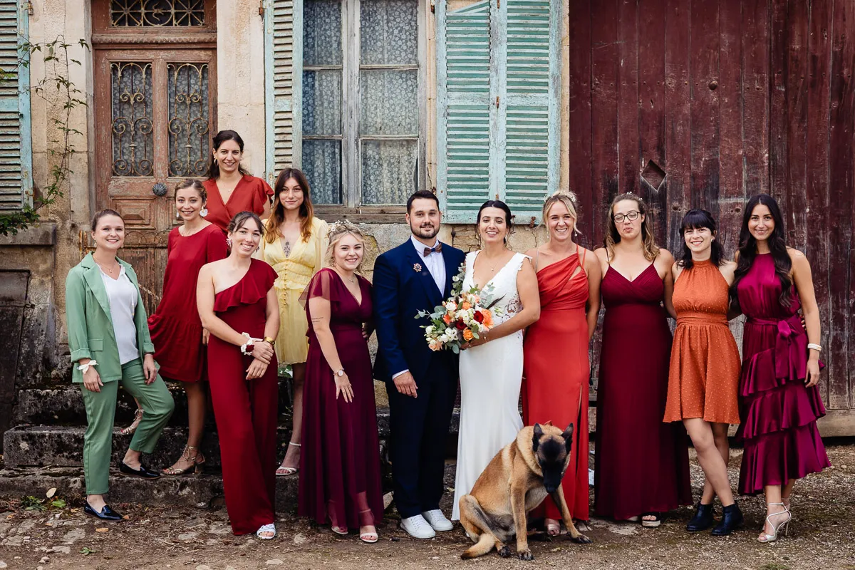 Un groupe de demoiselles d’honneur et de garçons d’honneur debout devant une vieille maison.