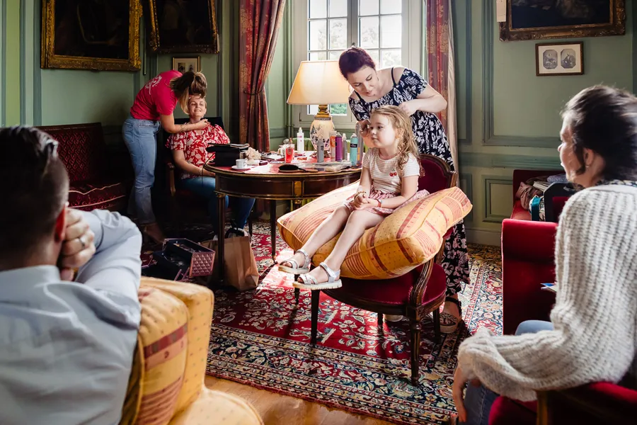 Un groupe de personnes assises dans une pièce avec une fille assise sur une chaise.