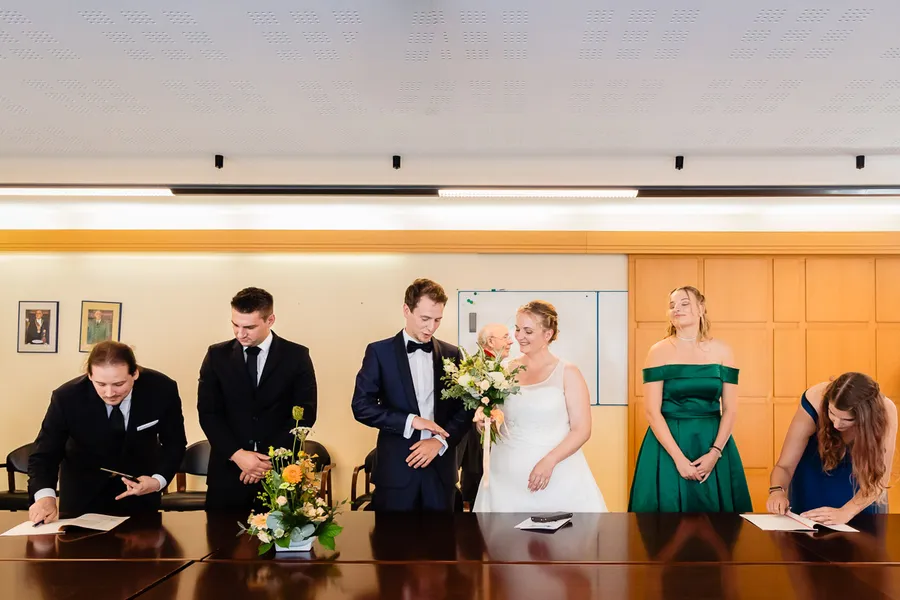 Un groupe de personnes signant un acte de mariage dans une pièce.