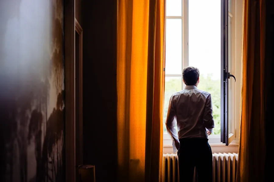 Un homme regarde par la fenêtre d’une pièce.