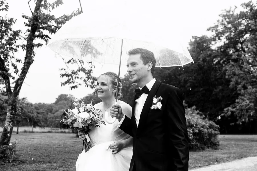 Une photo en noir et blanc des mariés tenant un parapluie.