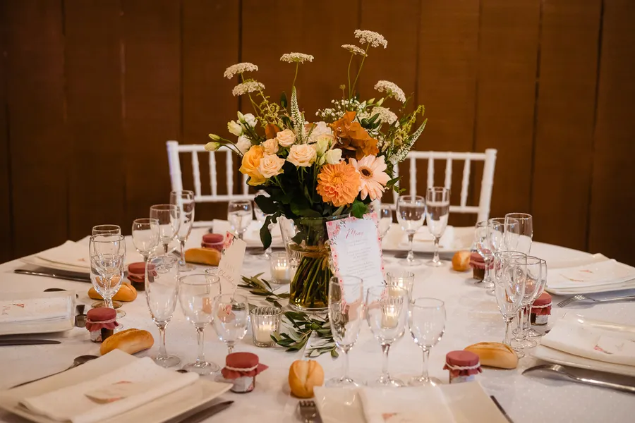 Une table dressée avec des fleurs orange et blanches.