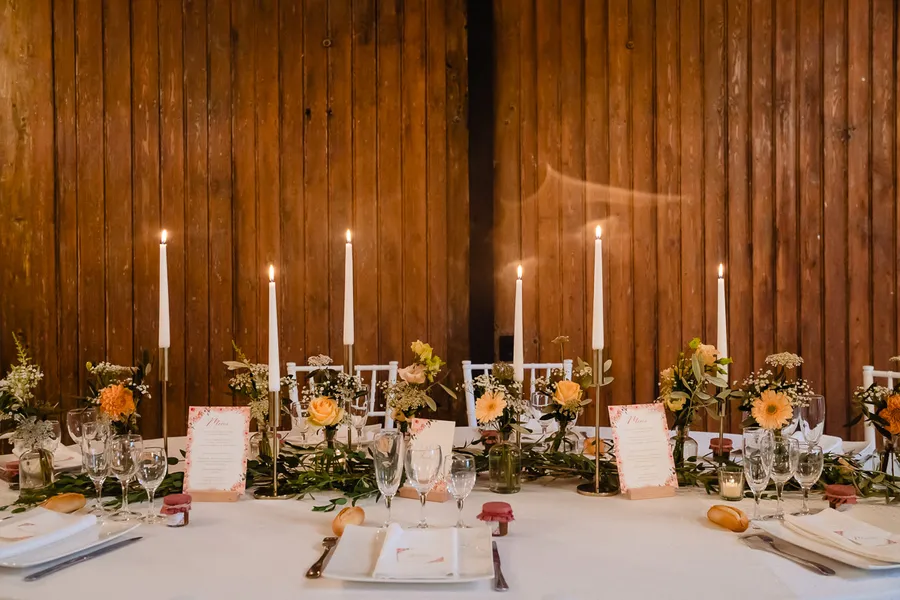 Une table de mariage dressée avec des bougies et des fleurs.